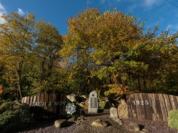 Porthllwyd memorial garden, Dolgarrog. Stone and slate memorial, blue sky, autumn trees.