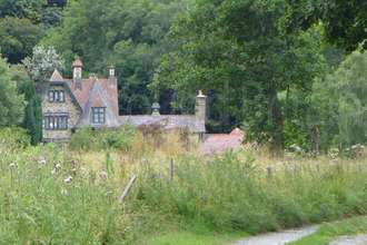 Pensychnant Conservation Centre. A large old brick house partially hidden by trees and overgrown grassland.