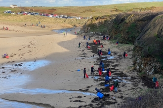 Porth Trecastell filled with volunteer beach cleaners