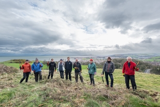 Nine volunteers post in a line for a picture in front of a landscape view