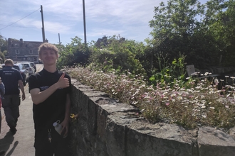 Lewis Bainbridge, student placement posing by a wall giving a thumbs up