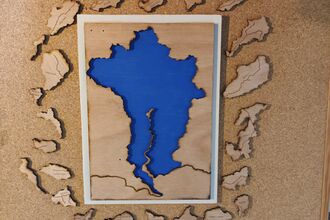 A wooden cut-out of the Conwy valley catchment area. The river catchment in blue, with different tributaries as jigsaw pieces to fit into the valley.