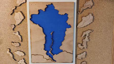 A wooden cut-out of the Conwy valley catchment area. The river catchment in blue, with different tributaries as jigsaw pieces to fit into the valley.