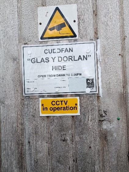 Photo of the door to the Spinnies Aberogwen Kingfisher Hide. The white sign read Cuddfan "Glas Y Dorlan" Hide