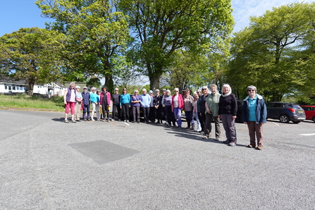 A group photo of Merched Mercher, a local women’s walking group standing together under leafy green trees before their guided walk at Cors Erddreiniog