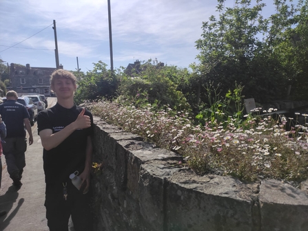 Lewis Bainbridge, student placement posing by a wall giving a thumbs up