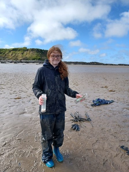 Anna Williams stands on a beach, in waterproof clothing and wellies, during one of her volunteer sessions