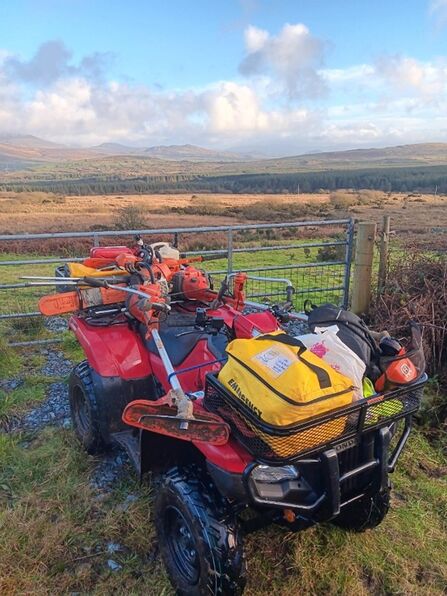 Quad bike and trailer loaded with various reserve management tools with blue sky and white clouds in background