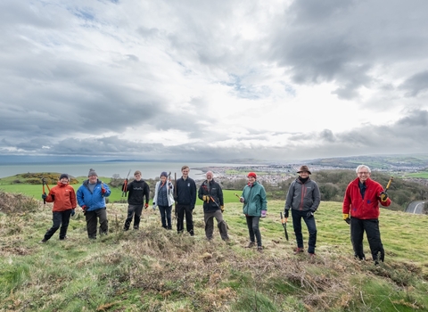 Nine volunteers post in a line for a picture in front of a landscape view