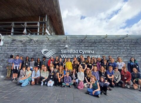 A group of young people posing outside the Senedd in Cardiff