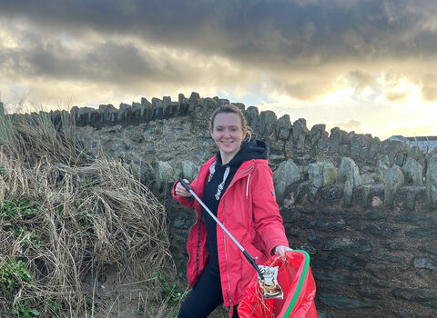 woman picking litter on beach 