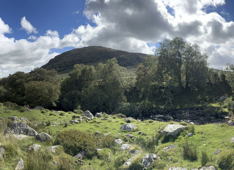 Panoramic image of Pwll Du, mountain landscape, sunny day, blue sky, white clouds.